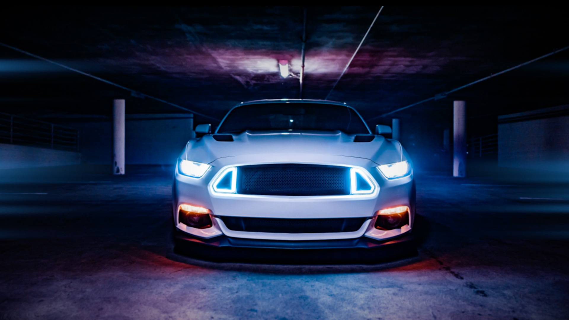 A white Mustang in a dramatically lit parking garage